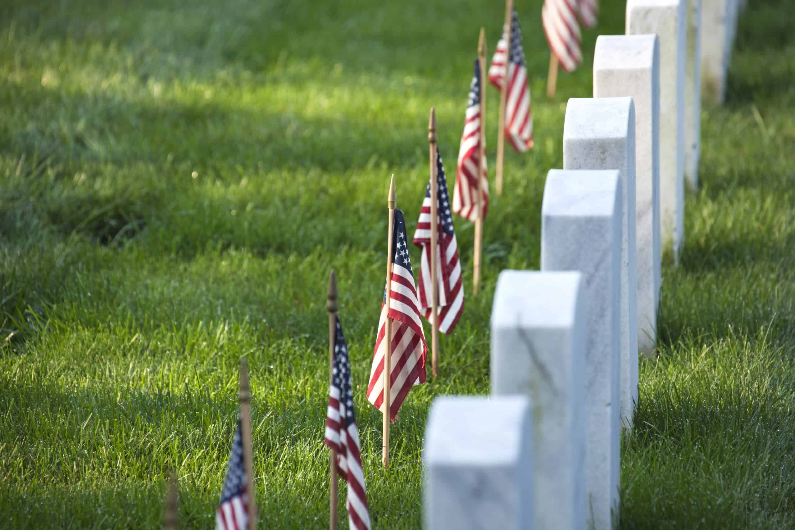 american flags in front of tombstones at AHRQ7GY scaled