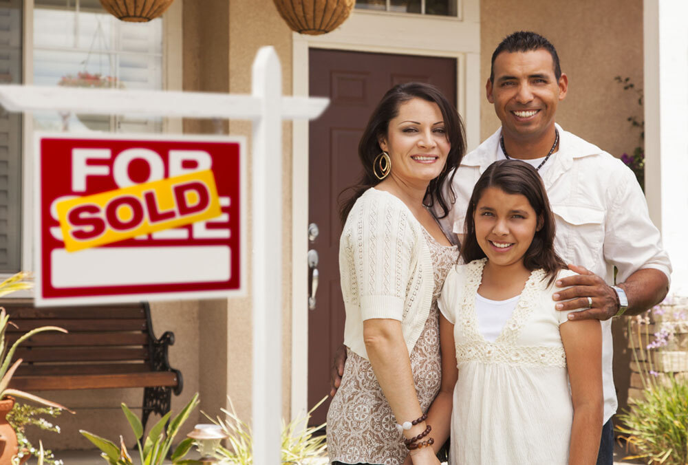 A veteran stands with his family in front of their new home.