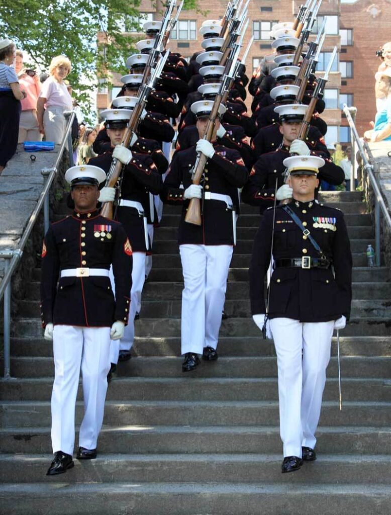 Military servicemen walking uniformly down a set of stairs in an outside setting